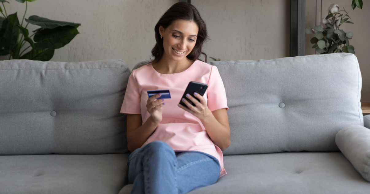 Happy woman holding her credit card while checking the payment methods on her phone
