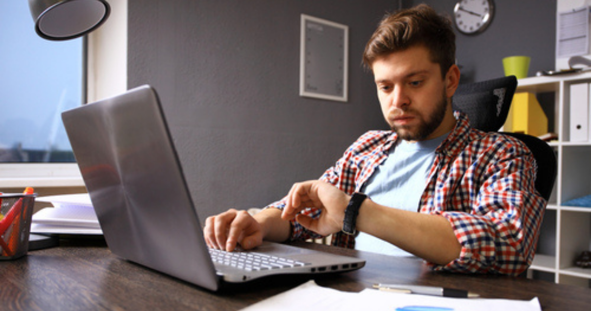 Man overwhelmed with paperwork looking at his watch